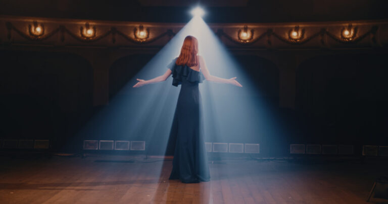 Young woman in elegant dress gesticulating and talking passionately with audience