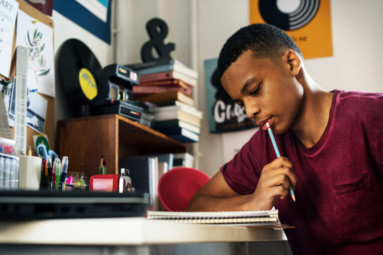 Teenage boy in a bedroom thinking and writing